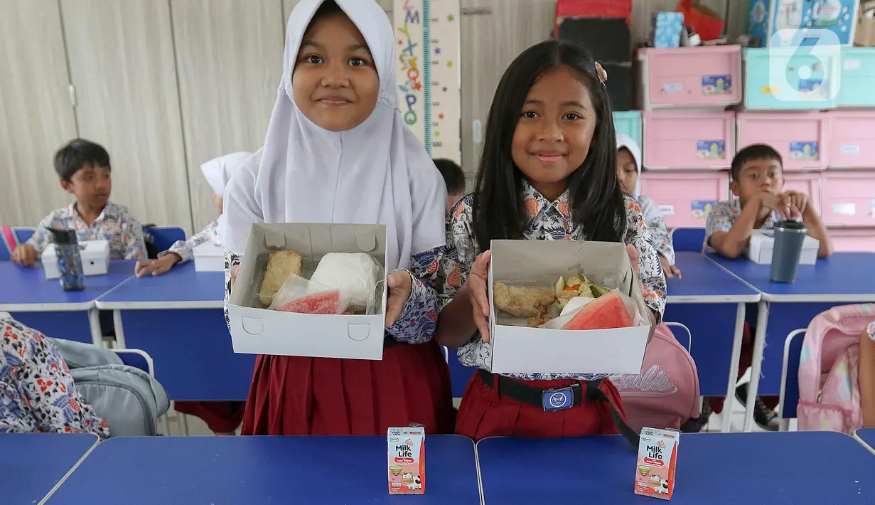 <p>Dua siswi Sekolah Dasar (SD) Angkasa 5 Halim Perdanakusuma memperlihatkan makanan yang tersaji di dalam kotak saat uji coba program makan bergizi gratis, Jakarta, Selasa (26/11/2024). (Liputan6.com/Herman Zakharia)</p>