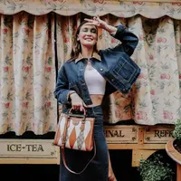 Luna Maya tampil denim on denim dengan jaket jeans crop top dengan krah cokelat dikombinasikan tank top crop top putih. Dipadukan slit skirt jeans.&nbsp;(@lunamaya)