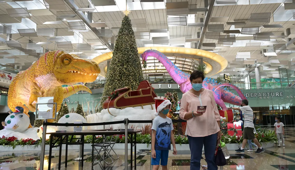 Orang-orang berfoto dengan latar dekorasi Natal di terminal 3 Bandara Changi Singapura (7/12/2020). Bandara Changi Singapura tampak sepi jelang menyambut Natal di Tengah Pandemi COVID-19. (Xinhua/Then Chih Wey)