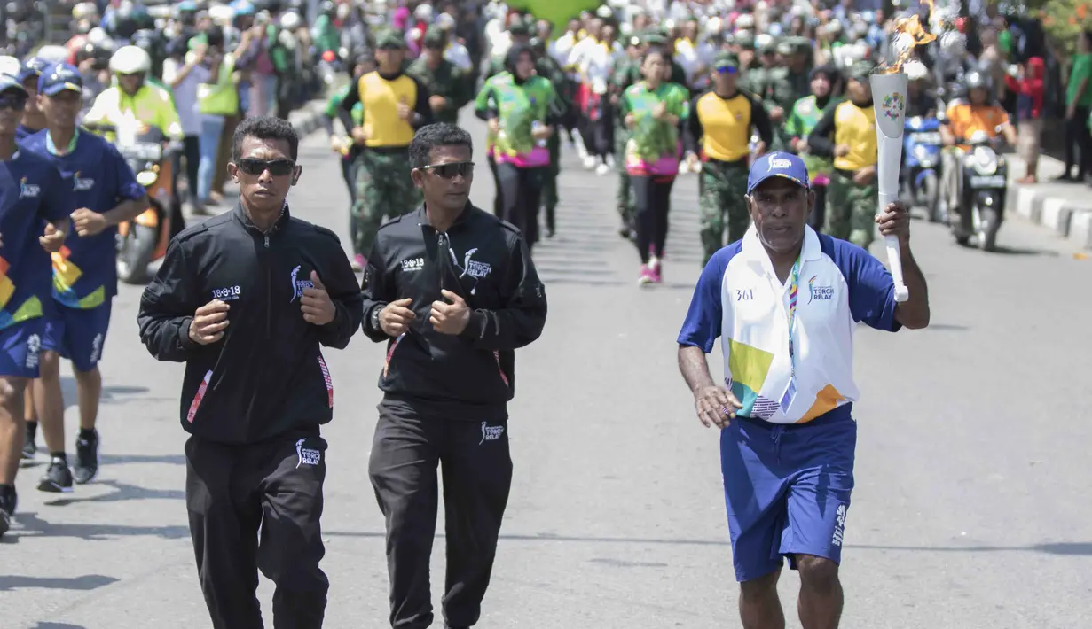 Legenda taekwondo Indonesia, Abdul Rojak, foto bersama mitra Grab usai membawa obor Asian Games melintasi Banjarmasin, Kalimantan Selatan, Senin (30/7/2018). Sebanyak 53 kota di Indonesia akan dilalui oleh obor Asian Games. (Bola.com/Reza Bachtiar)
