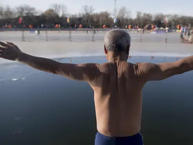 Seorang pria bersiap untuk melompat ke dalam danau Hou Hai yang beku di Beijing, China (24/1). (AFP Photo/Nicolas Asfouri)