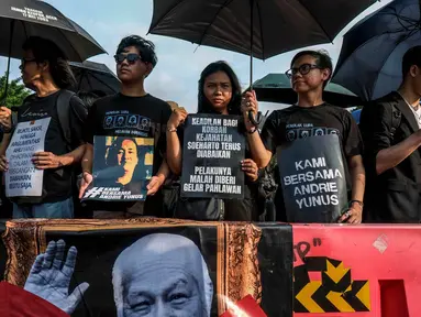 Para aktivis memegang payung hitam dan poster selama Aksi Kamisan di depan Istana Kepresidenan, Jakarta, Kamis 30 April 2026. Hari ini, Kamis 30 April 2026, Aksi Kamisan ke-906 dilaksanakan seperti biasa. (BAY ISMOYO/AFP)
