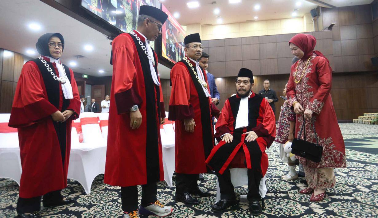 Setelah menyelesaikan seluruh rangkaian prosesi purnabakti, Anwar Usman berpamitan dengan para hakim aktif dan berjalan menuju pintu keluar. Tampak dalam foto, Anwar Usman (kedua kanan duduk) beristirahat usai mengikuti prosesi wisuda purnabakti di Ruang Sidang Mahkamah Konstitusi (MK), Jakarta, Senin (13/4/2026). (Kapanlagi.com/Budy Santoso)
