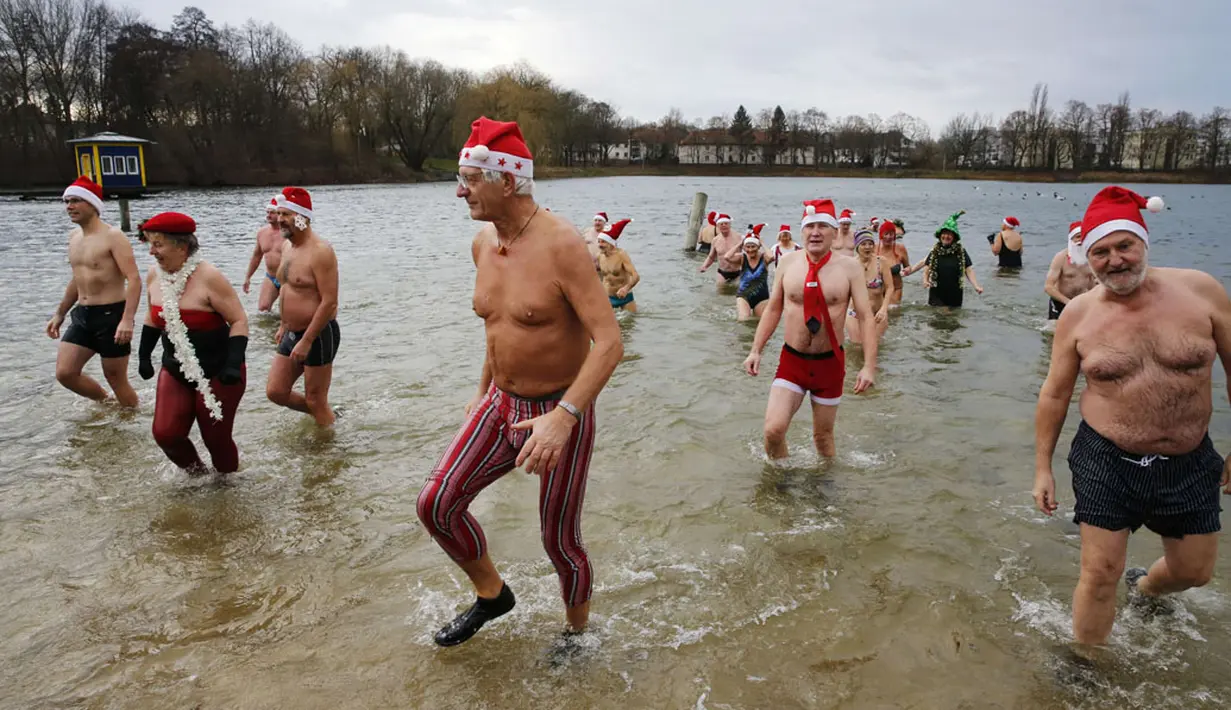 Puluhan anggota klub renang es "Berliner Seehunde" merayakan Natal dengan berenang di danau Orankesee, Berlin (25/12/2014). (REUTERS/Fabrizio Bensch)