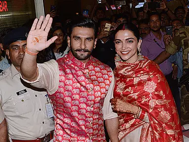 Pasangan pengantin baru, Ranveer Singh dan Deepika Padukone menyapa penggemar yang menyambut mereka di bandara internasional Mumbai, Minggu (18/11). Pasangan bintang Bollywood India itu baru saja kembali dari acara pernikahan mereka di Italia. (AFP)