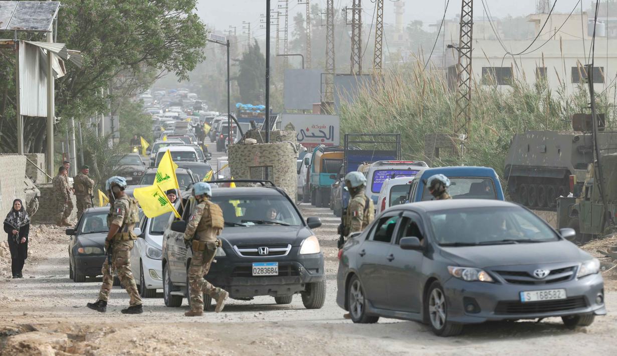 Gencatan senjata ini disambut dengan sukacita oleh warga Lebanon yang sebelumnya mengungsi guna menghindari serangan udara Israel. Tampak dalam foto, Kontingen Prancis dari Pasukan Sementara Perserikatan Bangsa-Bangsa di Lebanon (UNIFIL) berpatroli di daerah tersebut sementara warga yang mengungsi sambil mengibarkan bendera Hizbullah kembali ke rumah mereka melalui jalan darurat yang dibangun di lokasi jembatan Qasmieh yang hancur akibat serangan Israel, di wilayah Al-Qasmiyeh, Lebanon Selatan, pada Sabtu 18 April 2026. (MAHMOUD ZAYYAT/AFP)