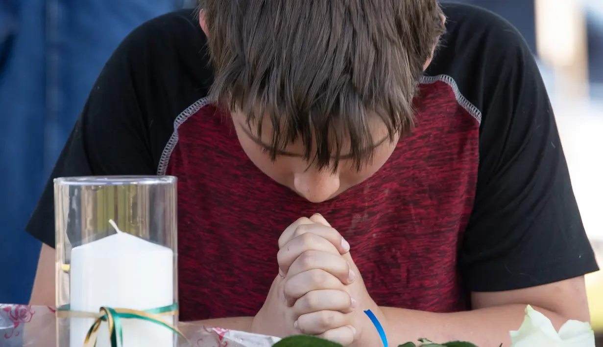 Trent Bolin (13) berdoa di depan lilin untuk mengenang korban penembakan di sekolah Santa Fe, Texas, Amerika serikat, Jumat (18/5). (Stuart Villanueva The Galveston County Daily News via AP)