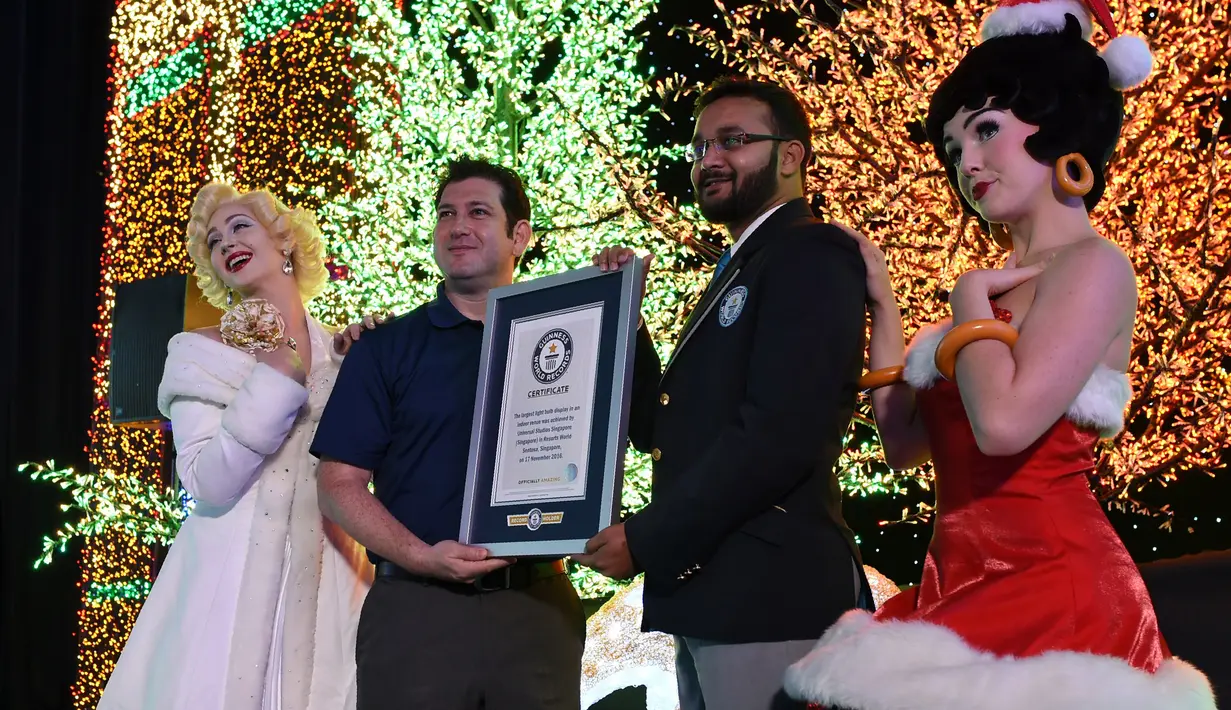 Pihak Guinness World Record menyerahkan piagam kepada Universal Studio Singapore yang telah berhasil memecahkan rekor dunia hiasan lampu Natal sebanyak 824.961 buah, Kamis (17/11).  (AFP PHOTO/ Roslan Rahman)