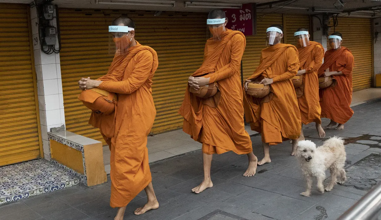 Para biksu Buddha memakai pelindung wajah untuk melindungi diri dari virus corona COVID-19 saat mengumpulkan sedekah di Bangkok, Thailand, Selasa (31/3/2020). Hingga 30 Maret 2020 sore, jumlah kasus COVID-19 di Thailand sebanyak 1.524 positif, 229 sembuh, dan 9 meninggal. (AP Photo/Sakchai Lalit)