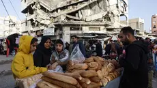 Warga Palestina menjual roti di dekat bangunan yang hancur di pasar Zawiya, Kota Gaza, pada Rabu 18 Februari 2026. Menyambut bulan suci Ramadan 1447 Hijriah, warga Palestina di Kota Gaza memadati Pasar Al-Zawiya. (Omar AL-QATTAA/AFP)