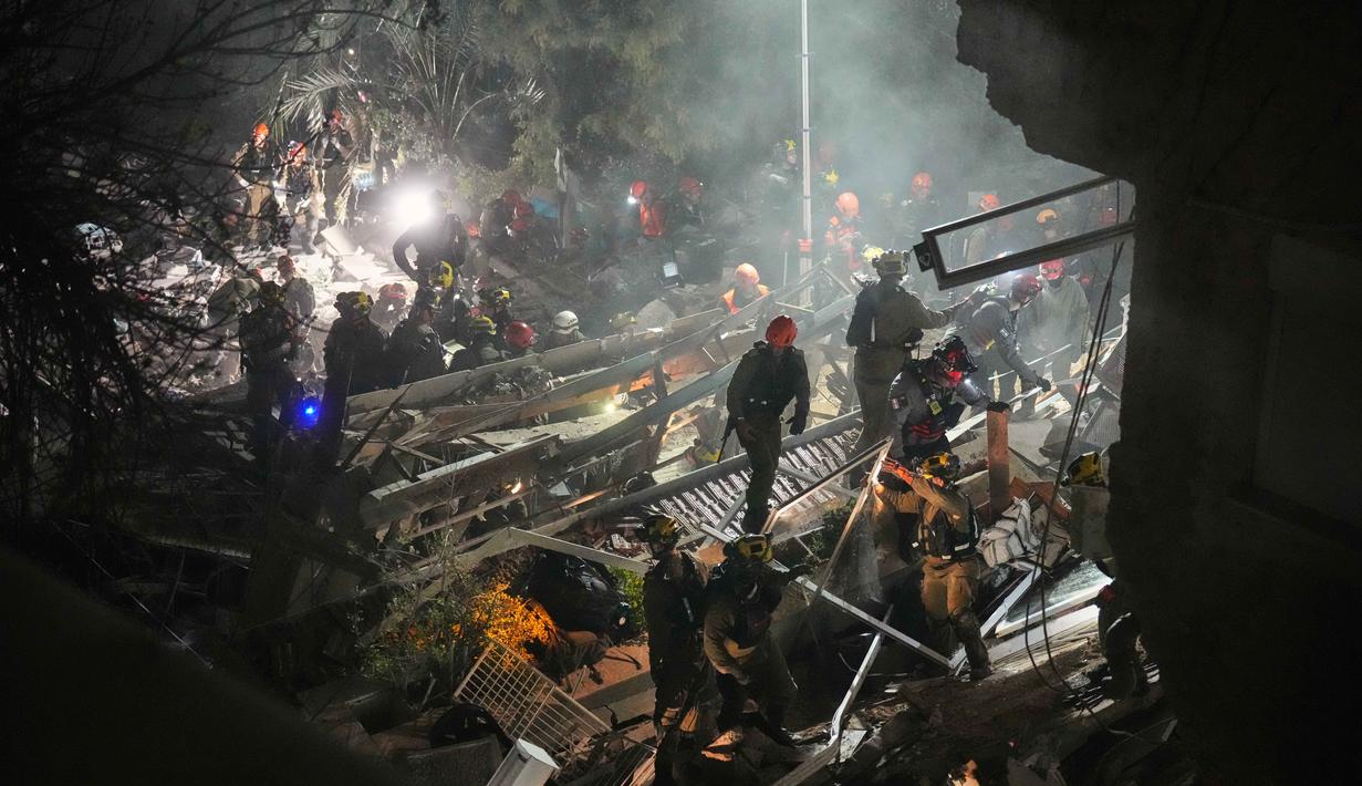 Pasukan keamanan Israel dan tim penyelamat melakukan upaya pencarian korban di tengah reruntuhan bangunan tempat tinggal yang dihantam rudal Iran di Haifa, Israel, Minggu, 5 April 2026. Rudal Iran menghantam sebuah bangunan tempat tinggal di Kota Haifa, Israel. (AP Photo/Ariel Schalit)
