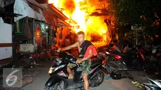 Seorang warga menyelamatkan diri dari kebakaran yang terjadi di belakang Senayan City, Jakarta, Minggu (3/7) dini hari. Sejumlah rumah semi permanen terbakar 38 mobil pemadam kebakaran dikerahkan. (Liputan6.com/Helmi Afandi)