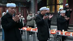 Di kota-kota dengan populasi Hui yang besar, seperti Linxia, suasana Ramadan terasa sangat kental dengan aktivitas berbagi sahur dan buka puasa bersama. Tampak dalam foto, warga Muslim etnis Hui Tiongkok membaca doa sebelum berbuka puasa di sebuah masjid selama minggu terakhir bulan suci Ramadhan di Beijing pada 17 Maret 2026. (Adek BERRY/AFP)