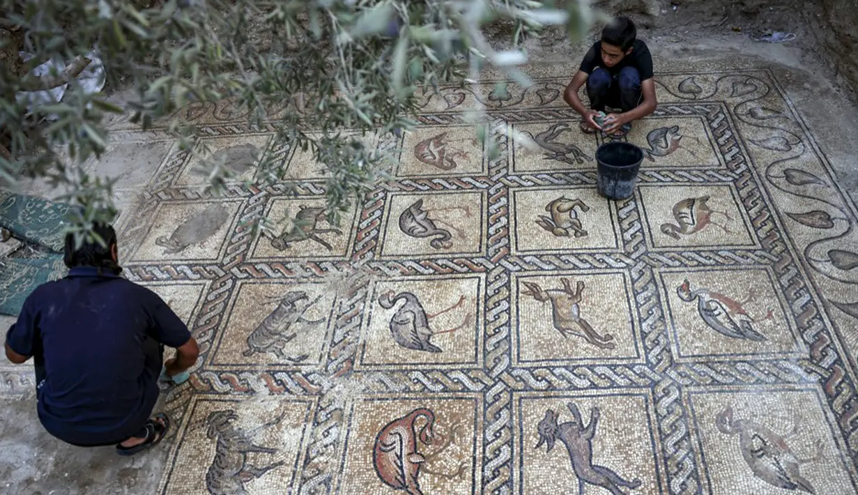 Petani Palestina Salman al-Nabahin dan putranya menemukan mosaik era Bizantium yang ditemukan di Bureij, Jalur Gaza, Palestina, 18 September 2022. Para ahli menyebutnya sebagai salah satu harta arkeologi terbesar yang pernah ditemukan di Jalur Gaza. (MOHAMMED ABED/AFP)