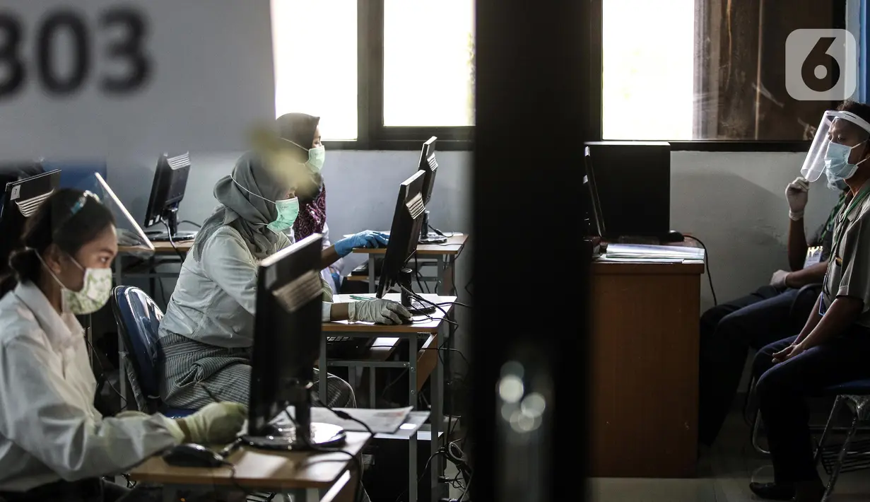 Pengawas dan peserta mengenakan masker, pelindung wajah, dan sarung tangan saat mengikuti Seleksi Bersama Masuk Perguruan Tinggi Negeri (SBMPTN) di Universitan Negeri Jakarta, Minggu (5/7/2020). Sebanyak 42.463 peserta mengikuti SBMPTN dengan prosedur protokol kesehatan. (Liputan6.com/Faizal Fanani)