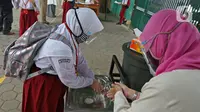 Seorang murid mencuci tangan sebelum memasuki sekolah  SD Negeri 6, Bekasi, Jawa Barat, Selasa (4/8/2020). Pemerintah setempat memberikan izin kepada enam sekolah untuk melakukan uji coba pembelajaran tatap muka selama satu bulan. (Liputan6.com/Herman Zakharia)