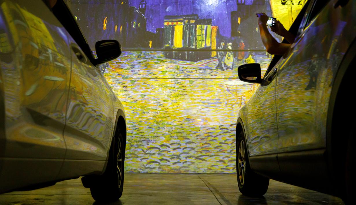 Orang-orang duduk di mobil mereka menikmati pameran seni Vincent Van Gogh di Toronto, Ontario, Kanada pada 3 Juli 2020. Pameran seni di masa pandemi Covid-19 mendatangkan ide kreatif para penyelenggara kegiatan dengan memamerkan hasil karya seni lewat konsep drive-in. (Cole BURSTON/AFP)