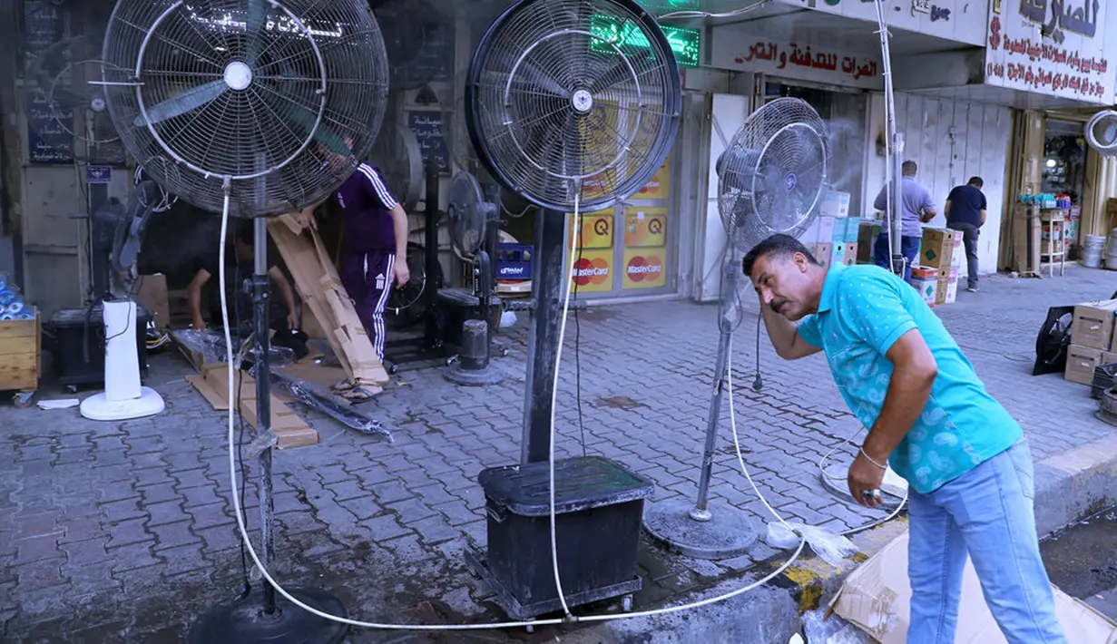 Seorang pria mendinginkan diri dari cuaca panas di bawah kipas angin di Baghdad, Irak, Kamis (1/7/2021). Pemerintah Irak menetapkan 1 Juli 2021 sebagai hari libur resmi di Baghdad karena gelombang panas yang menyengat. (AP Photo/Khalid Mohammed)