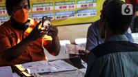 Petugas memotret warga penerima bantuan sosial (bansos) di kawasan Kedoya Selatan, Jakarta Barat, Rabu (28/7/2021). Selain bansos dari APBD DKI Jakarta, sekitar 738 ribu orang lainnya mendapatkan bantuan yang disalurkan oleh pemerintah pusat melalui Kementerian Sosial. (Liputan6.com/Johan Tallo)