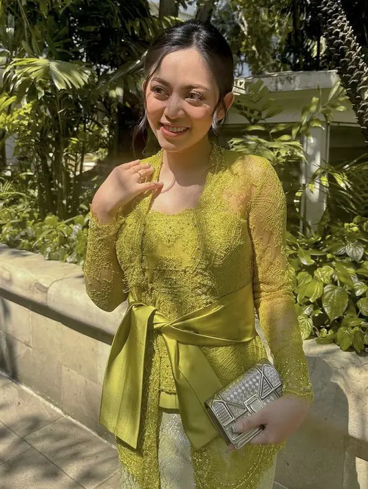 Rambutnya disanggul modern dengan sedikit poni membingkai wajahnya. Makeupnya dibuat flawless dengan blush on pink diserasikan dengan warna lipstiknya. (@rachelvennya)