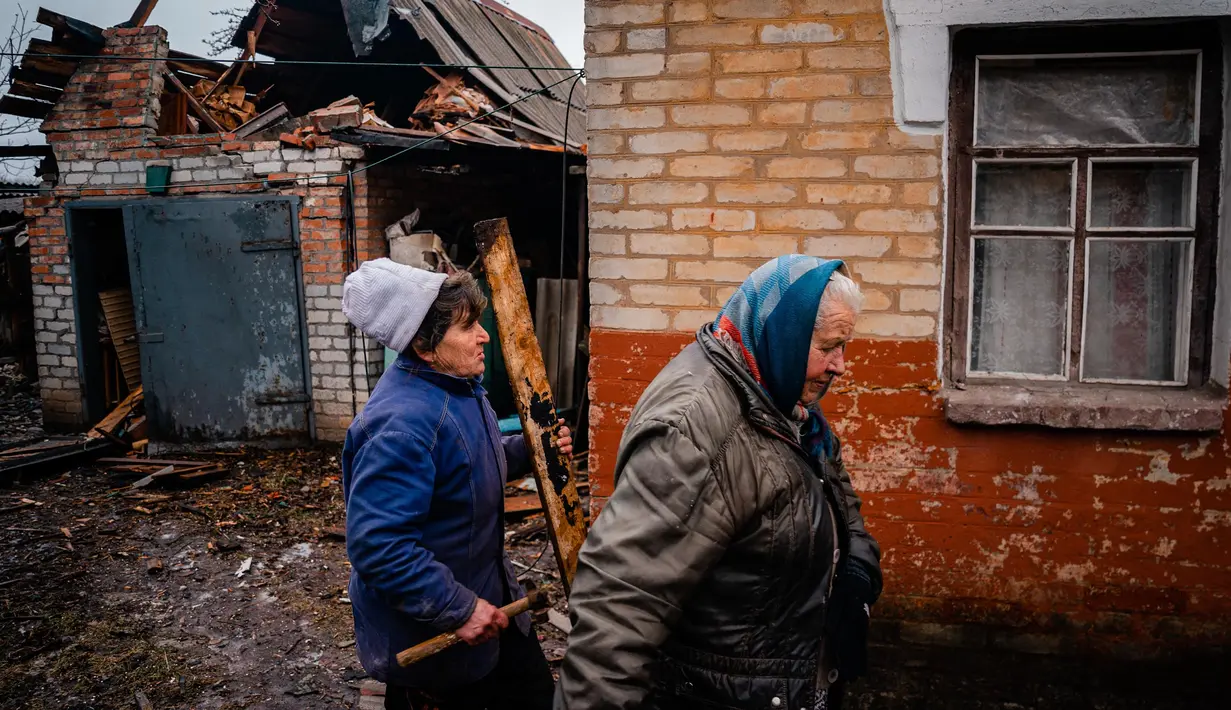 Seorang wanita berjalan di dekat rumah dengan jendela yang rusak setelah penembakan di Chasiv Yar, dekat Bakhmut pada 28 Februari 2023. Militer Ukraina mengatakan pada hari Selasa, Rusia menggempur permukiman di sekitar Bakhmut yang memiliki populasi sebelum perang sekitar 70.000 orang, namun kini menjadi reruntuhan. (Dimitar DILKOFF/AFP)