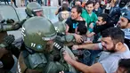 Para pengunjuk rasa mencoba membebaskan rekannya yang ditahan oleh polisi anti huru hara saat demonstrasi di luar kedutaan AS di Santiago, Chili (14/4). Mereka melakukan aksi menentang serangan AS ke Suriah. (AP / Esteban Felix)