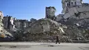 Seorang pria berjalan melewati bangunan yang  hancur di Salaheddine, Aleppo, Suriah, 20 Januari 2018. Gejolak krisis ekonomi menyebabkan lonjakan harga makanan dan kebutuhan dasar di Suriah. (12/6/2020). (AP Photo/Hassan Ammar, File)