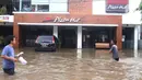 Warga melintas di depan pertokoan yang terendam banjir di Kawasan Bendungan Hilir (Benhil), Jakarta Pusat,  Selasa (25/2/2020). Salah satu wilayah terdampak banjir yakni kawasan Benhil hingga membuat akses jalan untuk sementara terputus.  (Liputan6.com/Angga Yuniar)