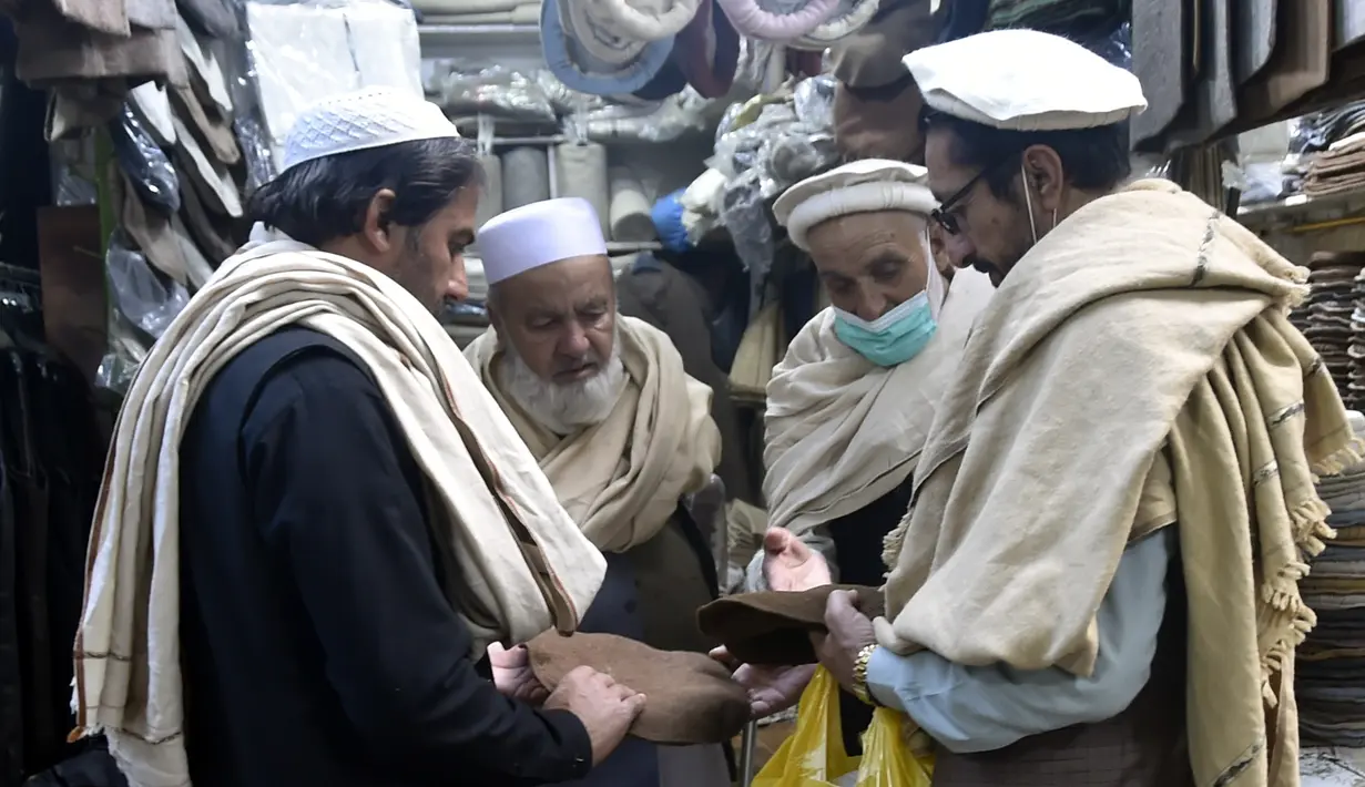 Orang-orang membeli topi tradisional di sebuah toko topi di Peshawar, Pakistan barat laut, pada 28 Desember 2020. Topi tradisional yang terbuat dari bahan wol ini sangat populer di kalangan warga Pakistan selama musim dingin. (Xinhua/Saeed Ahmad)