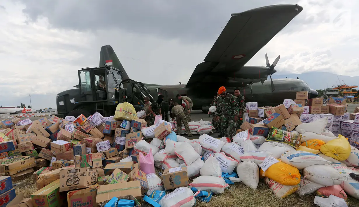Prajurit TNI dibantu tentara Amerika Serikat mendistribusikan bantuan logistik yang tiba di Bandara Mutiara Sis Al-Jufri, Palu, Sulawesi Tengah, Minggu (7/10). Bantuan asing tiba menggunakan pesawat Hercules. (Liputan6.com/Fery Pradolo)