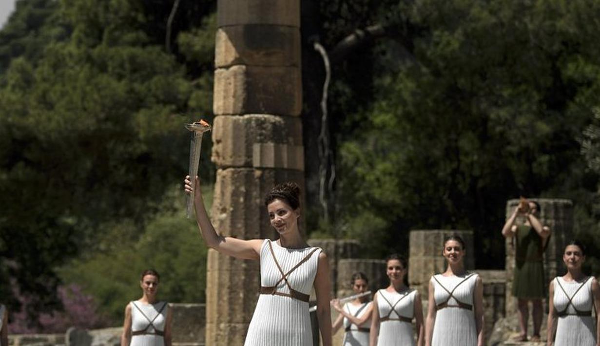 Aktris Yunani, Katerina Lechou, mengangkat obor api olimpiade yang baru saja dinyalakan dalam suatu upacara di Candi Hera yang terletak di bekas kota tua Olympia, Yunani, Kamis (21/4/2016). (AFP/Aris Messinis)