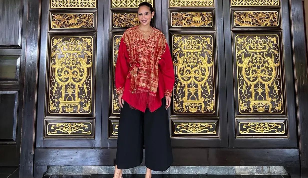 <p>Istri Menteri Perindustrian Agus Gumiwang, Loemongga Haoemasan tampil elegan dibalut blouse motif songket warna merah-kuning dan celana kulot warna hitam. [@loemongga]</p>