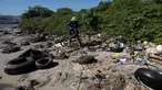 Seorang pria mengumpulkan sampah di pantai Pulau Pombeba, Teluk Guanabara, Rio de Janeiro, Brasil, Senin 17 Februari 2025. (Pablo PORCIUNCULA/AFP)