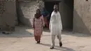 Mohammad Ikram berjalan bersama ibunya Rizia Bibi di rumah mereka di sebuah desa dekat kota Samundri, Pakistan, Minggu (25/10/2020). Dia tinggal di kota pedesaan terpencil di provinsi Punjab dan kecacatan fisiknya tidak menghalangi impian masa kecilnya untuk bermain snooker. (AP Photo/Anjum Naveed)