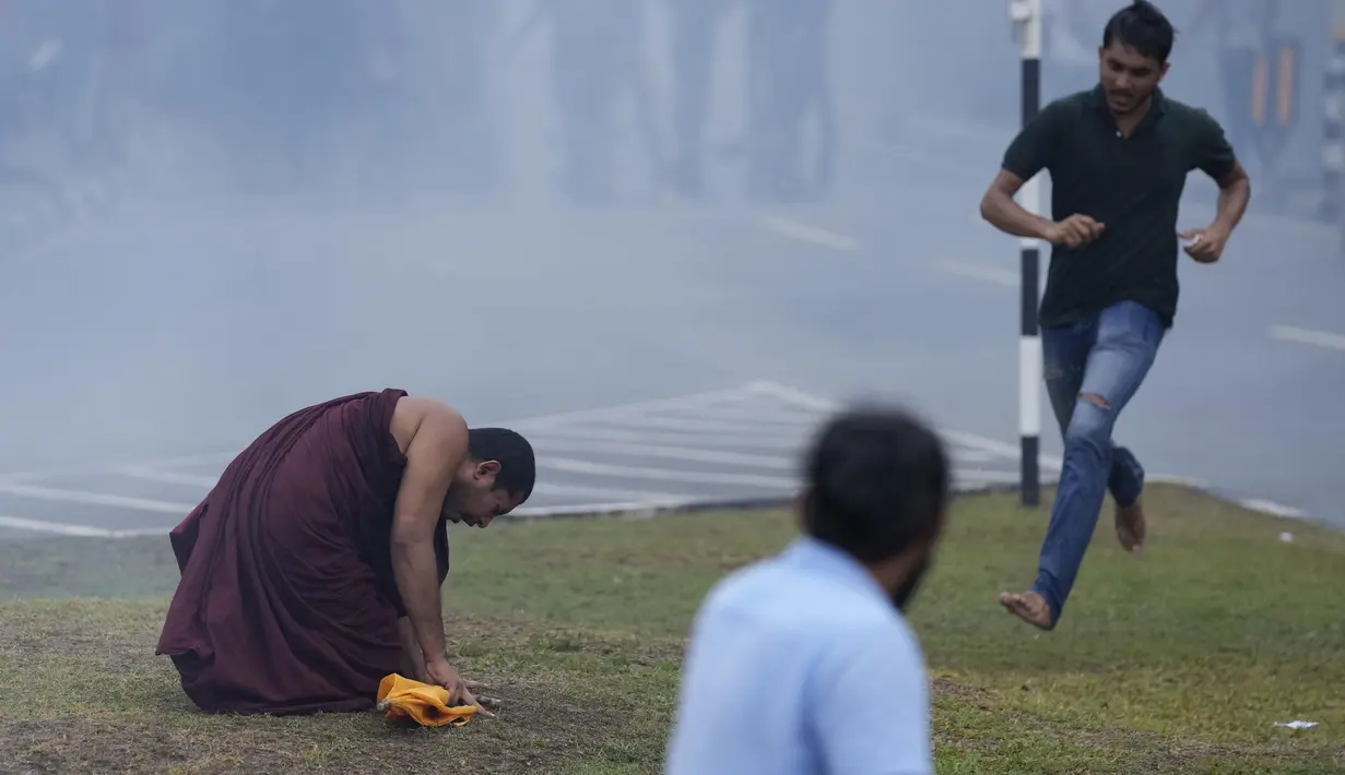 Seorang biksu Buddha Sri Lanka bereaksi setelah menghirup gas air mata yang digunakan oleh polisi untuk membubarkan protes anti-pemerintah oleh mahasiswa Sri Lanka menuntut pengunduran diri presiden Gotabaya Rajapaksa di dekat parlemen di Kolombo, Sri Lanka (8/4/2022). (AP Photo/Eranga Jayawardena)