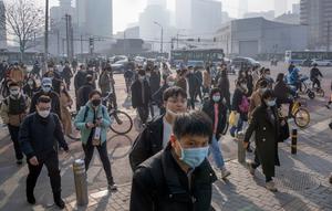 Komuter yang memakai masker berjalan melintasi persimpangan di kawasan pusat bisnis pada hari dengan tingkat polusi udara yang tinggi di Beijing, China, Senin (6/3/2023). Pejabat ekonomi China menyatakan keyakinannya bahwa mereka dapat memenuhi target pertumbuhan tahun ini sekitar 5 persen dengan menghasilkan 12 juta pekerjaan baru dan mendorong pengeluaran konsumen setelah berakhirnya kontrol antivirus yang membuat jutaan orang tetap di rumah. (AP Photo/Mark Schiefelbein)