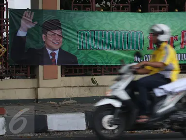 Pengendara motor melintasi spanduk bertuliskan 'Muhaimin for President' di pagar Masjid Sunda Kelapa, Jakarta, Sabtu (12/9). Pemasangan spanduk itu melanggar UU tentang larangan penggunaan tempat ibadah sebagai tempat kampanye. (Liputan6.com/Angga Yuniar)