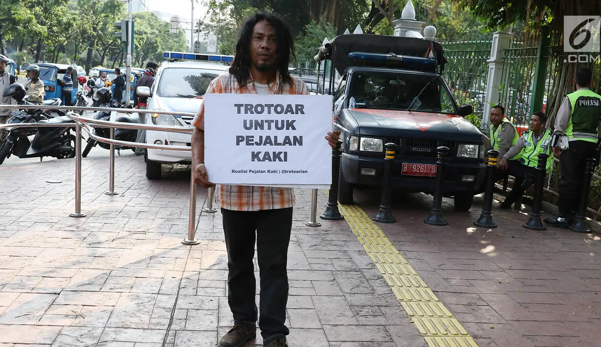 Aktivis Koalisi Pejalan Kaki (KPK) melakukan aksi sambil membawa poster himbauan di sepanjang trotoar kawasan Monas, Jakarta, Jumat (28/7). Aksi tersebut dilakukan untuk mengembalikan trotoar sesuai fungsinya. (Liputan6.com/Immanuel Antonius)