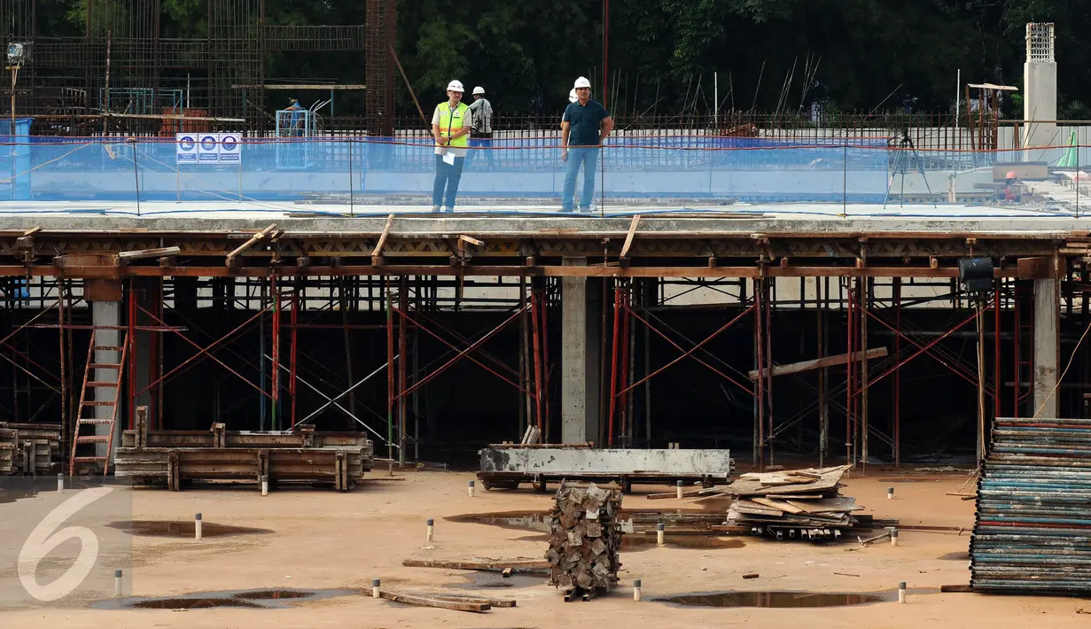 Pekerja berdiri di atas salah satu kolam Stadion Renang Gelora Bung Karno, Jakarta, Jumat (24/3). Stadion Renang GBK ditarget selesai Oktober 2017 dan akan menjadi salah satu stadion renang terbesar di Asia. (Liputan6.com/Helmi Fithriansyah)