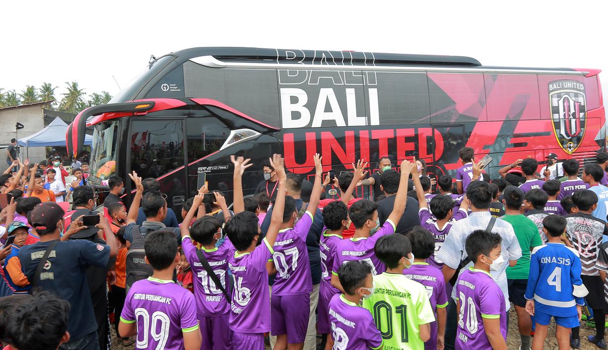 Sejumlah pemain SSB melambaikan tangan ke arah bus yang berisi pemain Bali United usai acara penyerahan bola ke 70 SSB se-bali. (Bola.com/ M Iqbal Ichsan)