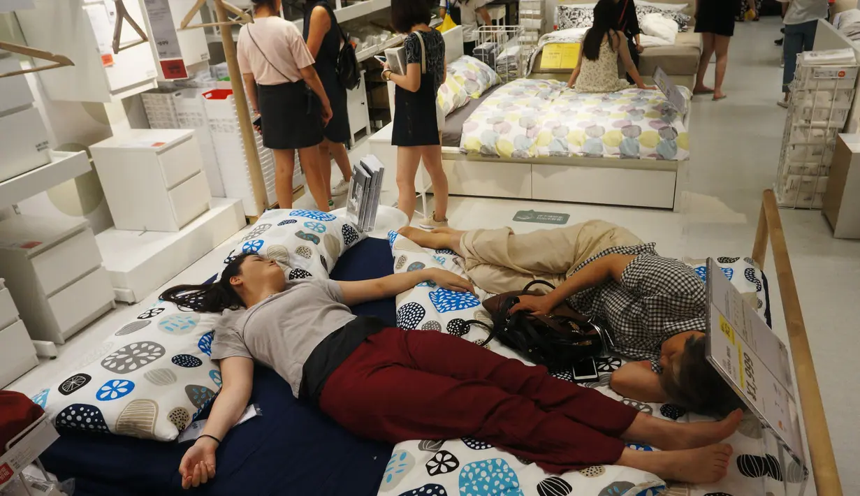 Pengunjung tidur di tempat tidur di sebuah pusat perbelanjaan menghindari panas di luar di Hangzhou, di provinsi Zhejiang timur China (24/7). Beberapa pekan terakhir China mengalami suhu udara yang cukup panas. (AFP Photo/Str/China Out)