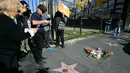 Beberapa bunga sebagai tanda belasungkawa dan penghormatan diletakkan di bintang Hollywood Walk of Fame milik aktor sekaligus sutradara Amerika Serikat, Rob Reiner, di Los Angeles, California. Tampak dalam foto, orang-orang mengambil foto bintang Hollywood Walk of Fame milik aktor sekaligus sutradara Amerika Serikat, Rob Reiner dan ayahnya, Carl Reiner, di Los Angeles, California, pada Senin 15 Desember 2025. (Frederic J. Brown/AFP)