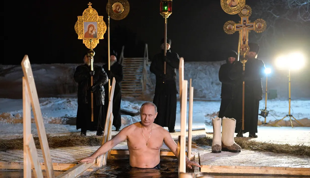 Presiden Rusia Vladimir Putin berendam di air dingin di Danau Seliger di desa Svetlitsa, Rusia (19/1). Ribuan pengikut Gereja Ortodoks Rusia akan berendam ke sungai dan kolam es merayakan Epiphany. (Alexei Druzhinin, Sputnik, Kremlin Pool Photo via AP)