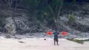 Seorang pria melambaikan jaket penyelamat saat meminta pertolongan ketika terdampar di Pulau Faradik, Mikronesia, 7 April 2016. Tiga orang pelaut terdampar setelah kapal yang mereka tumpangi tersapu ombak setinggi dua meter. (ENSIGN JOHN KNIGHT/NMCO/AFP)