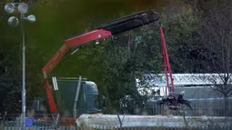 Crane mengevakuasi bangkai helikopter dari lokasi kecelakaan yang menewaskan pemilik Leicester City Vichai Srivaddhanaprabha di Leicester, Kamis (1/11). Helikopter yang ditumpangi Vichai terjatuh tak jauh dari Stadion King Power. (Aaron Chown/PA via AP)