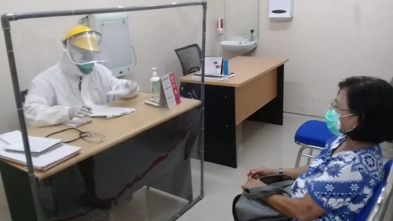 Dokter Elang Sumambar melayani konsultasi dengan kaca pembatas. (Foto: Liputan6.com/Felek Wahyu)