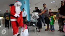 Santa Claus saat ingin memberikan hadiah kepada seorang anak di Bandara Soekarno Hatta, Tangerang, Banten, Selasa (22/12). Sejumlah orang berkostum santa claus membagikan coklat kepada penumpang yang berada dibandara. (Liputan6.com/Faisal R Syam)