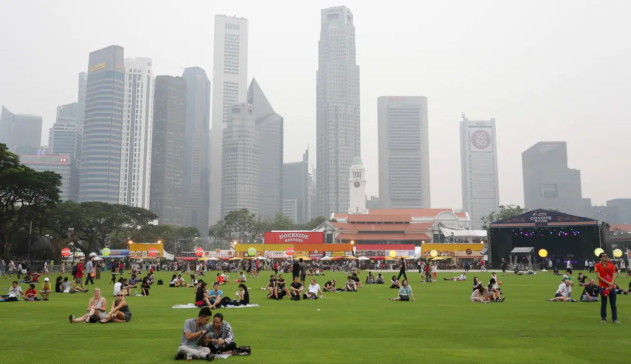 Sejumlah pendukung bersantai di rumput menunggu ajang sesi latihan Grand Prix Singapura F1 (18/9/2015). Kabut asap yang menyelimuti sirkuit tak menyurutkan pembalap untuk tetap melakukan pemanasan. (Singapore Grand Prix /Reuters)