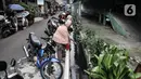 Warga memberi pakan ikan yang dipelihara di saluran air atau selokan di Jalan Lorong 103, Koja, Jakarta, Senin (1/3/2021). Warga setempat menyulap selokan sepanjang 100 meter tersebut menjadi kolam budi daya berbagai jenis ikan. (merdeka.com/Iqbal S. Nugroho)