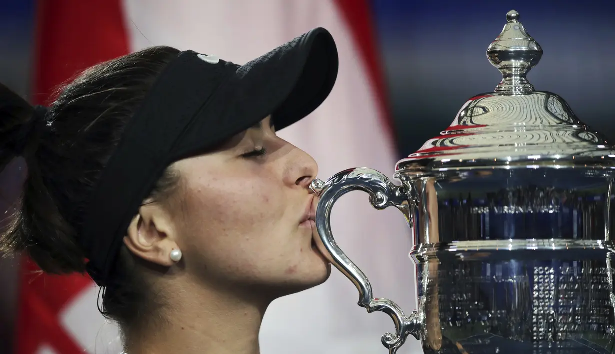 Petenis Kanada, Bianca Andreescu (19) mencium Piala AS Terbuka 2019 usai mengalahkan Serena Williams dari AS di final tunggal putri di New York (7/9/2019). Andreescu menang atas Serena 6-3, 7-5. (AP Photo/Charles Krupa)